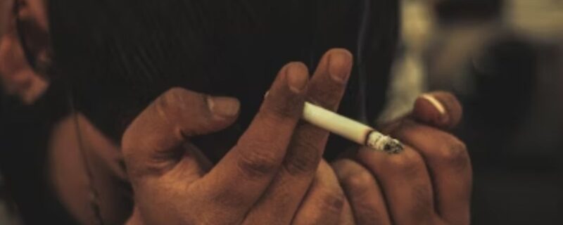 Understanding Dual Diagnosis: Treating Addiction and Mental Health Disorders Simultaneously 1 A man holds a cigarette with his face buried in his hands, appearing tired, disturbed, and trapped.