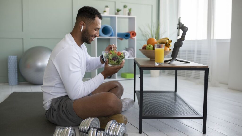 The Role of Nutrition and Fitness in Addiction Recovery 3 A man sits and rests after a workout, with a healthy selection of fruits and vegetables on the table in front of him.