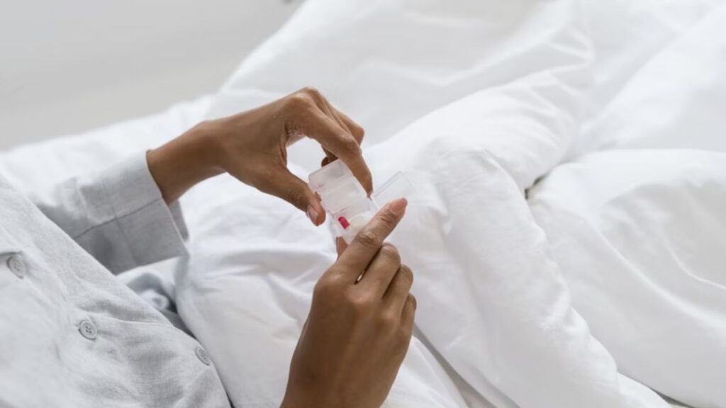 How to Support a Loved One Entering Addiction Treatment in Chicago 3 The hands and torso of a woman clutch a few tables while resting on a bed; the rest of her body is not visible.