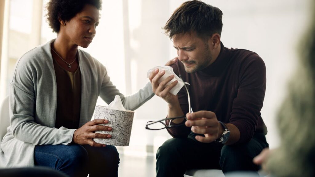 How to Support a Loved One Entering Addiction Treatment in Chicago 2 A man cries during a therapy session as his female therapist comforts him with a gentle hand on his shoulder.