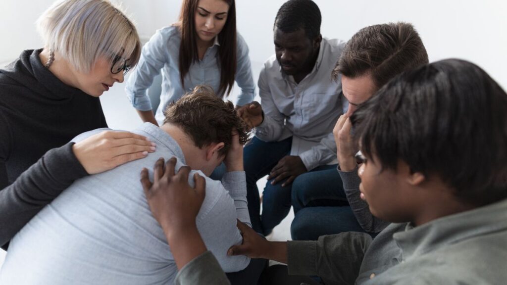 Finding the Best Addiction Support Groups in Chicago 4 Addiction support groups comforting a man who broke down in tears during a group therapy session.