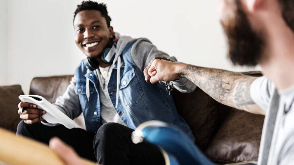 5 Signs You’re In Denial About Substance Use Disorder 4 Substance Use Disorder: A man in central focus presses his knuckles against another man in the foreground, whose back faces the camera.