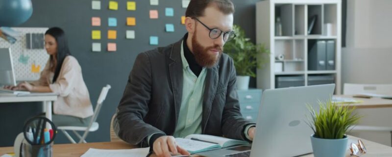 How Professionals Can Overcome Addiction While Maintaining Their Careers 1 A bearded male professional works intently on his computer, showing focus and determination during addiction recovery.